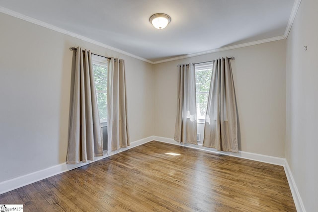 spare room featuring crown molding, baseboards, and wood finished floors