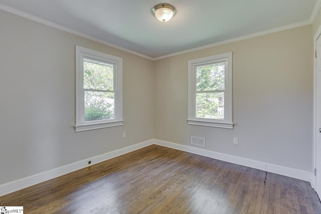 spare room featuring plenty of natural light, visible vents, baseboards, and wood finished floors