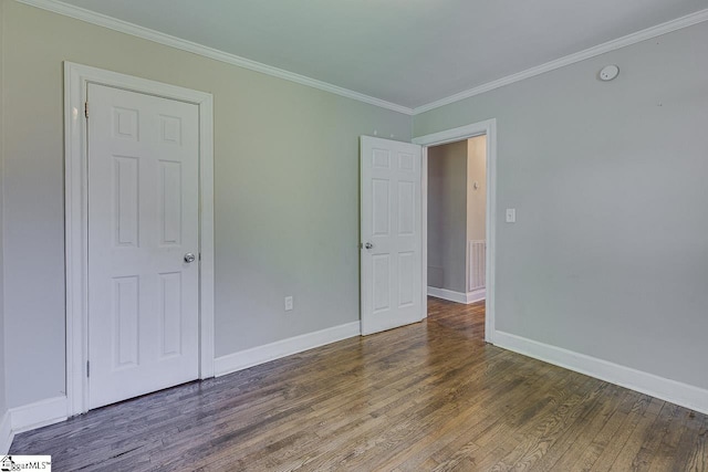 unfurnished bedroom with crown molding, wood finished floors, baseboards, and visible vents