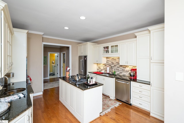 kitchen featuring a sink, appliances with stainless steel finishes, light wood-style floors, decorative backsplash, and a kitchen island