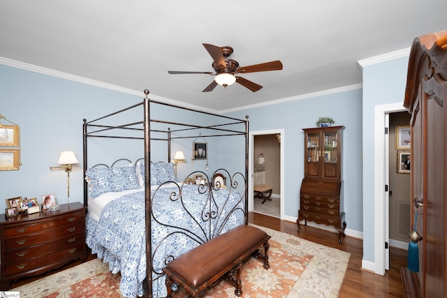 bedroom featuring crown molding, ceiling fan, ensuite bath, wood finished floors, and baseboards