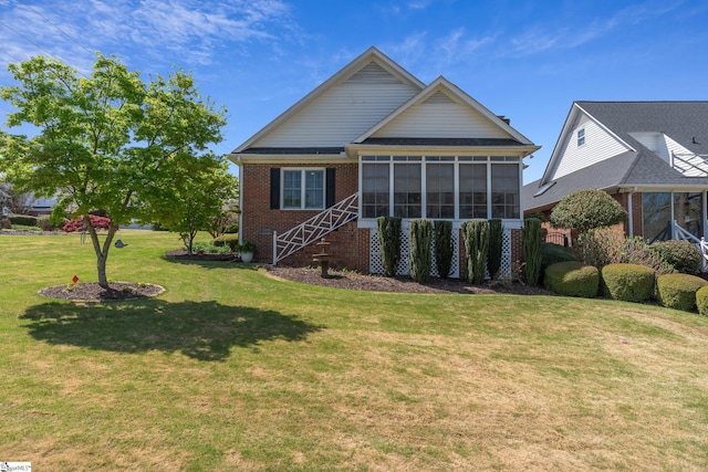 exterior space featuring a yard, brick siding, and a sunroom