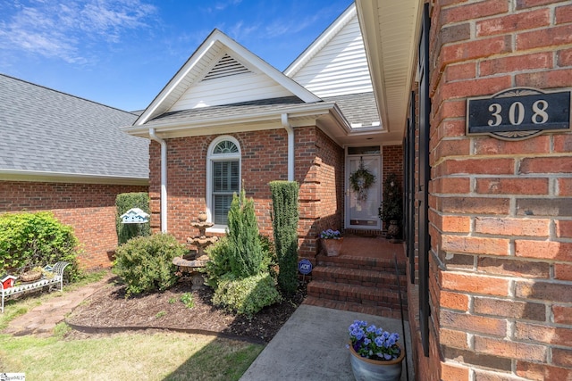 property entrance with a shingled roof and brick siding
