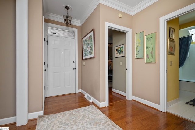 entrance foyer featuring visible vents, baseboards, crown molding, and wood finished floors