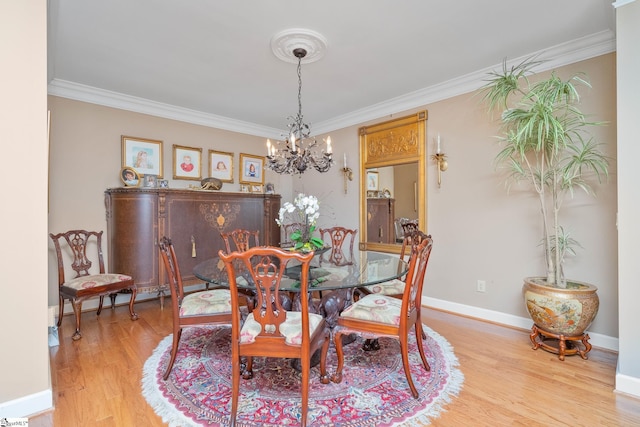 dining room featuring a notable chandelier, baseboards, crown molding, and wood finished floors