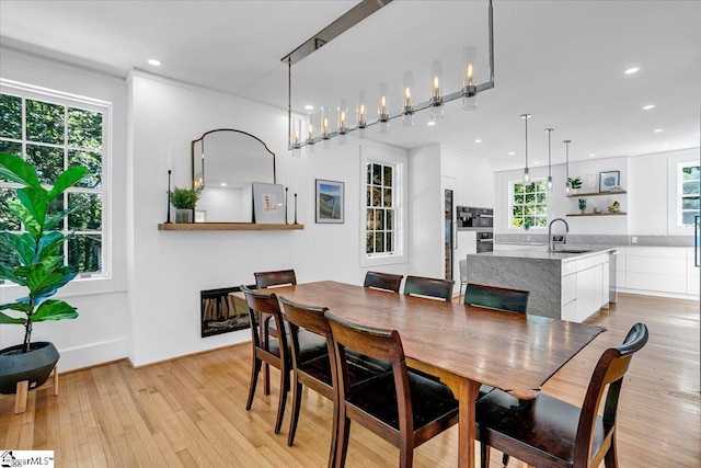 dining area with light wood-type flooring, crown molding, and recessed lighting