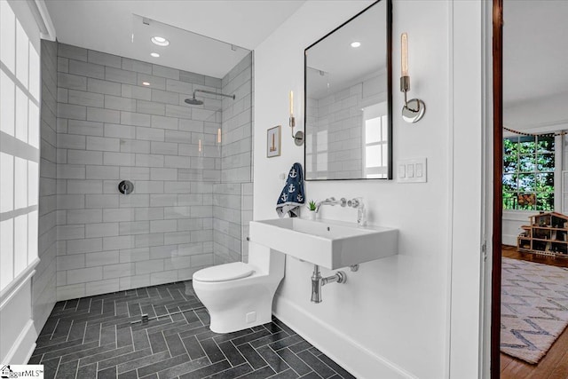 full bath with tiled shower, recessed lighting, toilet, a sink, and baseboards