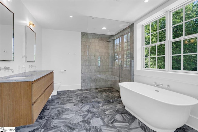 bathroom featuring a freestanding tub, toilet, a sink, walk in shower, and double vanity