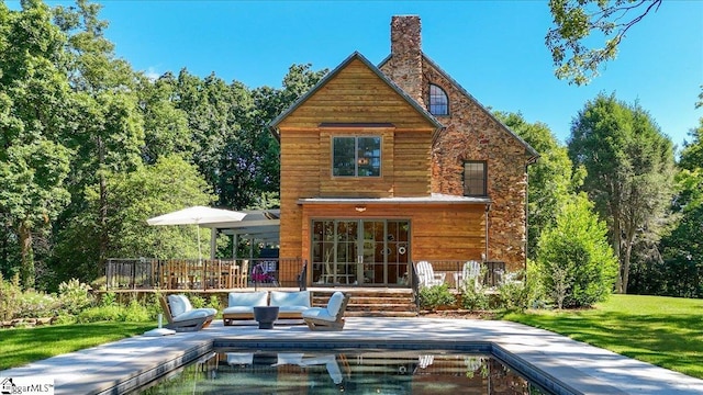 back of house with an outdoor pool, a chimney, and a yard