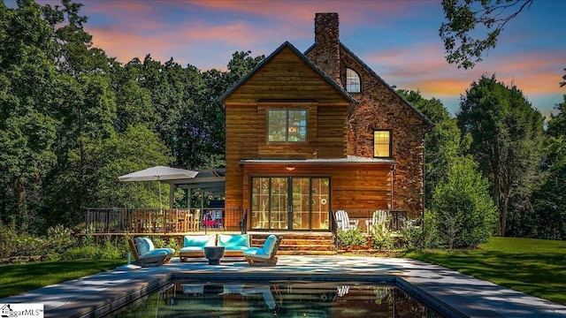 back of property with a yard, outdoor lounge area, and a chimney