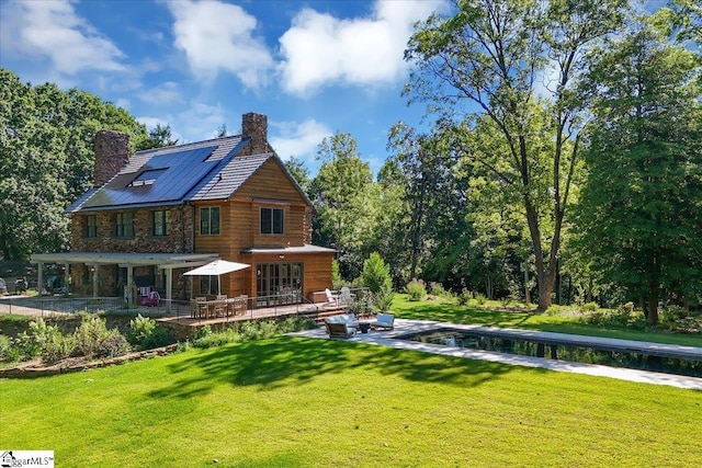 back of property featuring a patio, a lawn, and a chimney