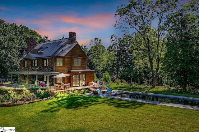 rear view of house with a chimney and a lawn