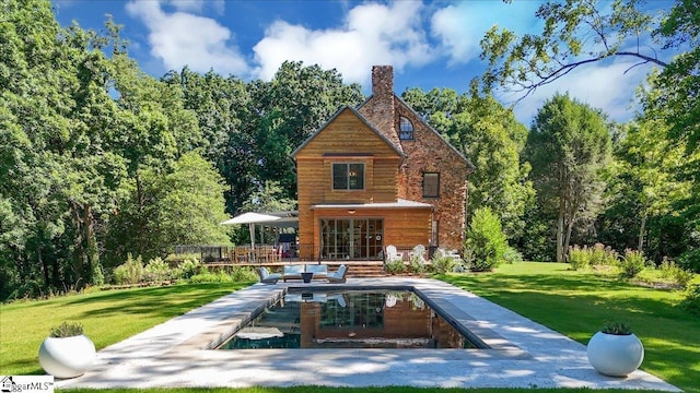 back of house with a yard, a wooden deck, and a chimney