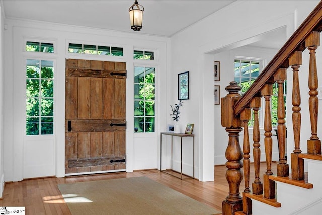 foyer with stairs, ornamental molding, and wood finished floors