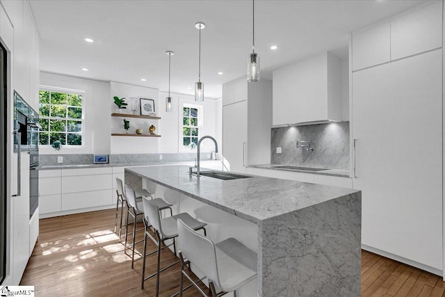 kitchen with modern cabinets, white cabinets, a healthy amount of sunlight, a sink, and backsplash