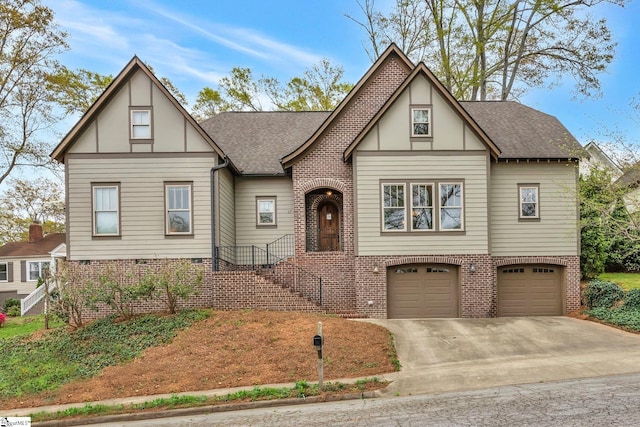 tudor home with brick siding, an attached garage, a shingled roof, and driveway