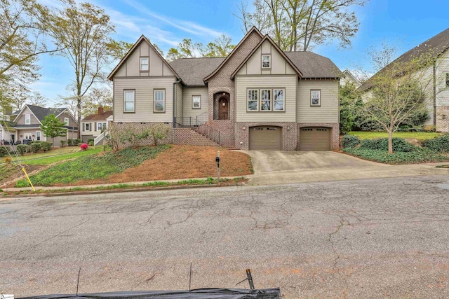 tudor home with brick siding, an attached garage, a shingled roof, and driveway