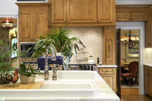 kitchen with brown cabinetry, tasteful backsplash, a sink, and light countertops