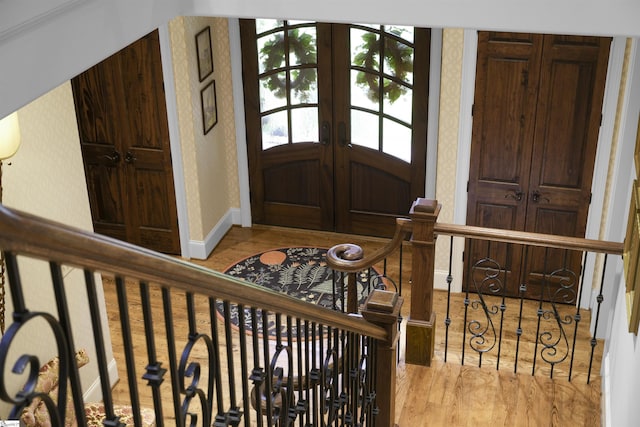 foyer with french doors, baseboards, wood finished floors, and wallpapered walls