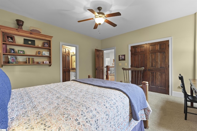 carpeted bedroom featuring a closet, ensuite bath, and a ceiling fan
