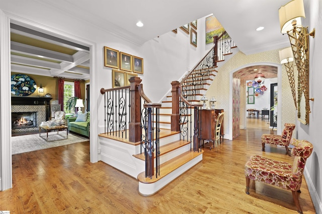 stairway featuring ornamental molding, arched walkways, coffered ceiling, and wood finished floors