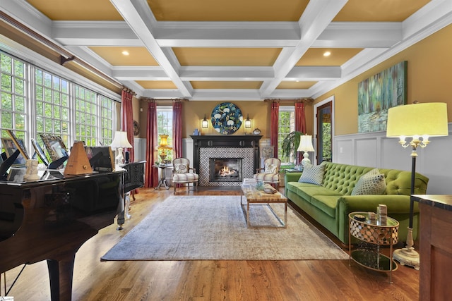 living area featuring wood finished floors, beamed ceiling, and a tiled fireplace