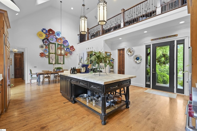 kitchen featuring a center island, light wood-style flooring, a high ceiling, and light countertops