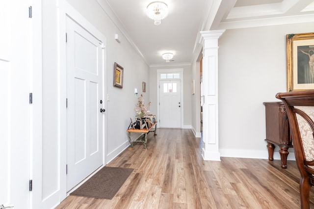 foyer with baseboards, light wood finished floors, ornate columns, and crown molding