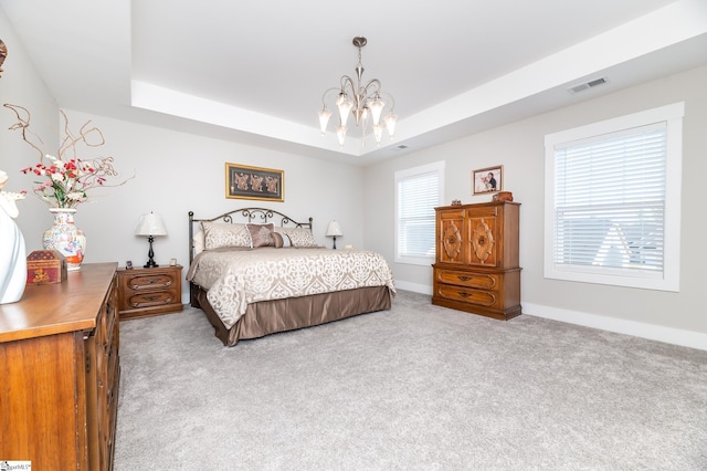 bedroom with visible vents, carpet flooring, a tray ceiling, and a chandelier