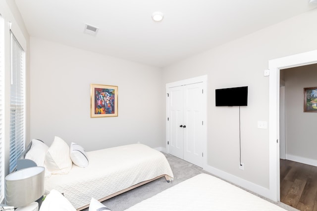 bedroom with visible vents, baseboards, a closet, and wood finished floors