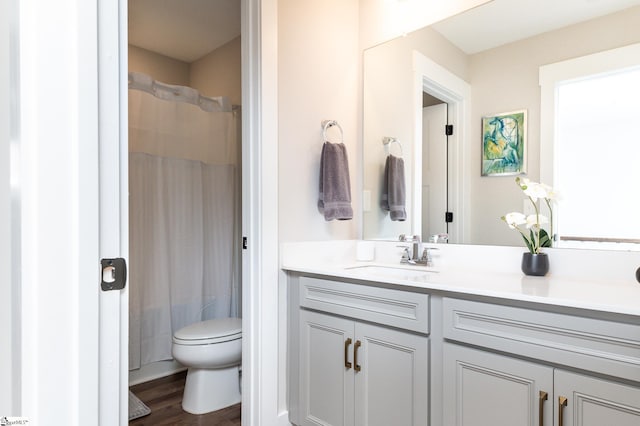 bathroom with toilet, a shower with shower curtain, vanity, and wood finished floors