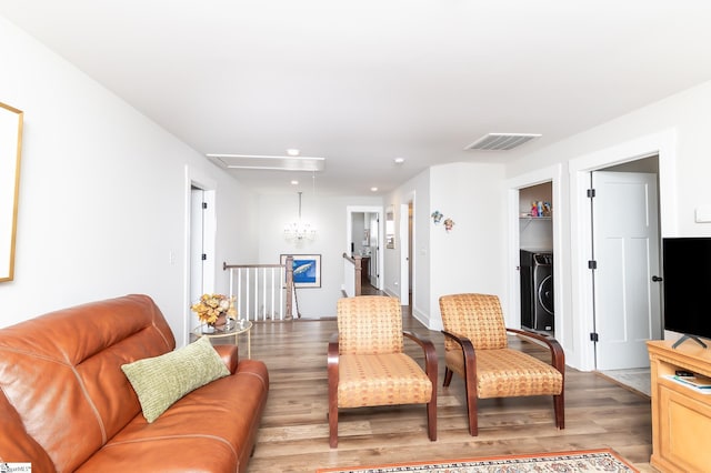 living room with washer / dryer, visible vents, light wood finished floors, and attic access