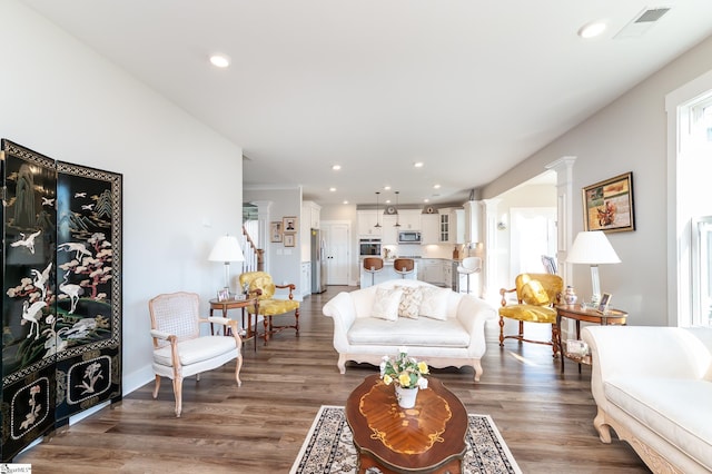 living room featuring recessed lighting, visible vents, ornate columns, and wood finished floors