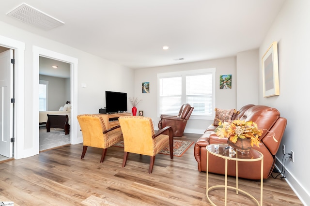 living area featuring a healthy amount of sunlight, light wood finished floors, and visible vents