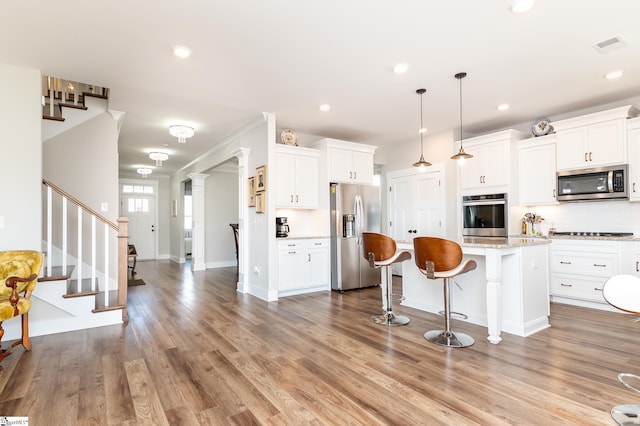 kitchen featuring a center island, a breakfast bar area, white cabinetry, and stainless steel appliances