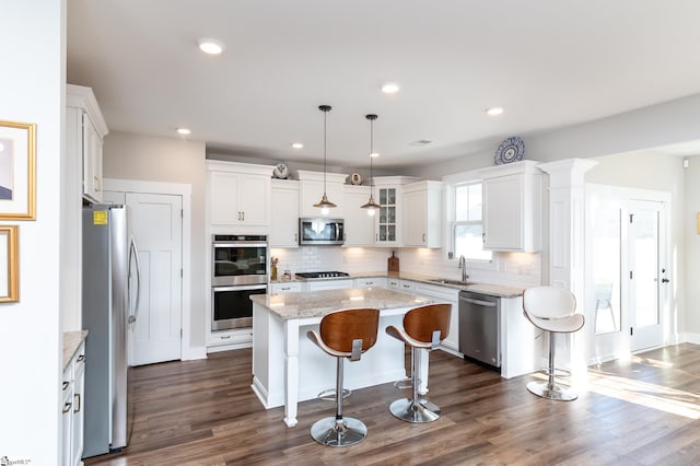 kitchen with tasteful backsplash, a center island, white cabinets, a breakfast bar area, and stainless steel appliances