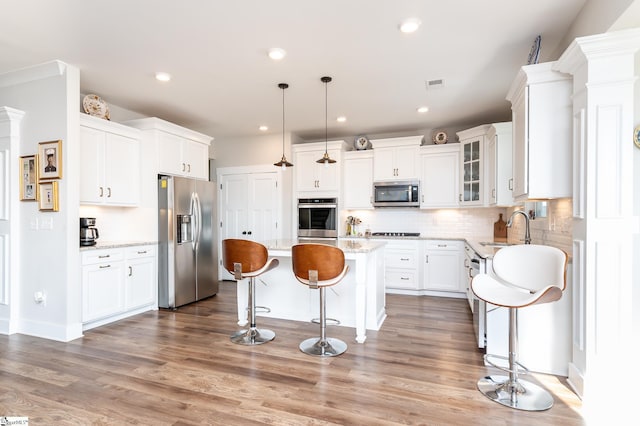 kitchen featuring a kitchen breakfast bar, a kitchen island, appliances with stainless steel finishes, a sink, and decorative backsplash