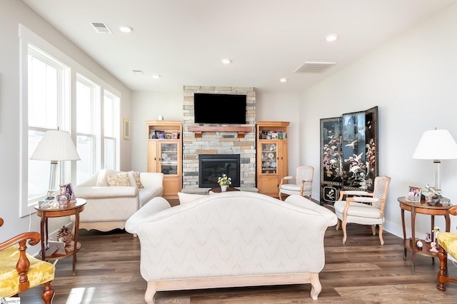 living room with recessed lighting, visible vents, a stone fireplace, and wood finished floors