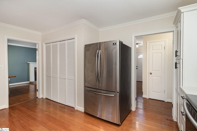kitchen with crown molding, freestanding refrigerator, light wood-type flooring, white cabinets, and baseboards