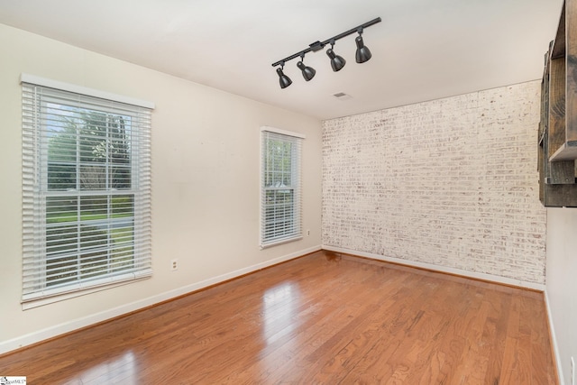 empty room with a healthy amount of sunlight, visible vents, and wood finished floors