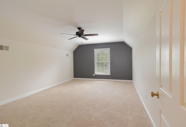 additional living space with baseboards, light carpet, visible vents, lofted ceiling, and ceiling fan