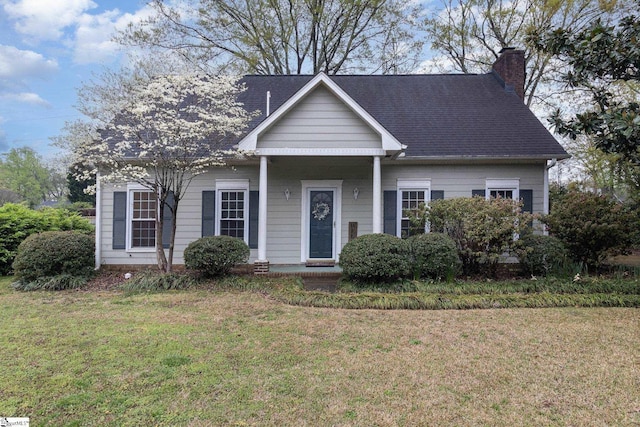 view of front of home featuring a chimney, a shingled roof, and a front yard