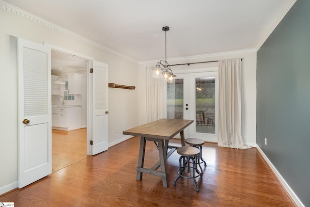 dining space featuring french doors, wood finished floors, baseboards, and ornamental molding