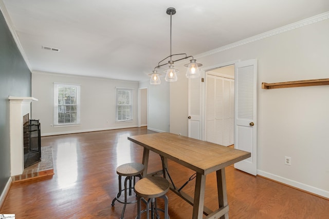 dining room with visible vents, baseboards, ornamental molding, and wood finished floors