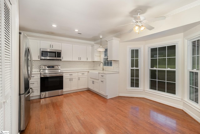 kitchen with white cabinetry, a ceiling fan, light wood-style floors, decorative backsplash, and stainless steel appliances