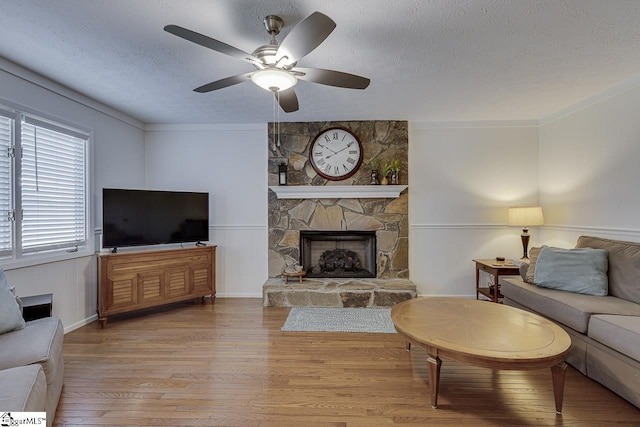 105 Berrywood Ct, Greer, SC 29650 - living area featuring a textured ceiling, a stone fireplace, ceiling fan, a wainscoted wall, and wood finished floors