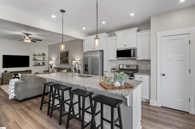 kitchen featuring a kitchen breakfast bar, white cabinets, dark wood-type flooring, stainless steel appliances, and a sink