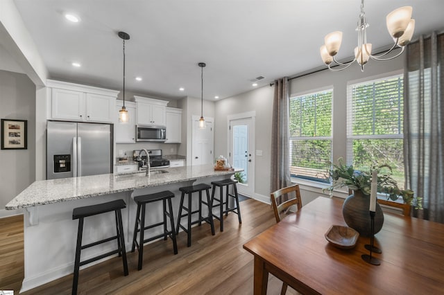 kitchen with white cabinets, a sink, dark wood-style flooring, a kitchen island with sink, and stainless steel appliances