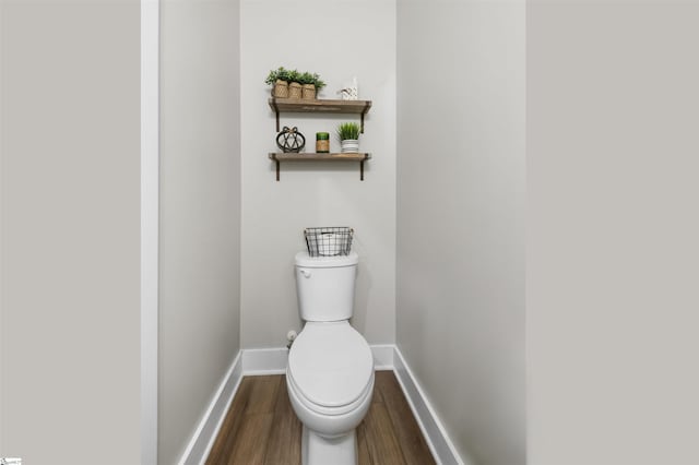 bathroom with toilet, baseboards, and wood finished floors