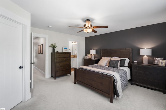 bedroom featuring light carpet, ensuite bath, baseboards, and ceiling fan